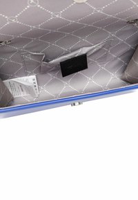 Vnitřek modré kabelky má elegantní šedou podšívku s diamantovým vzorem, černou etiketu a malou kapsičku na zip pro lepší organizaci.