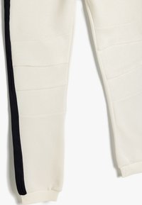 Off-white sweatpants med sort sidelæg, med teksturerede paneler, ribbede manchetter og en afslappet pasform. Blødt stof for komfort.
