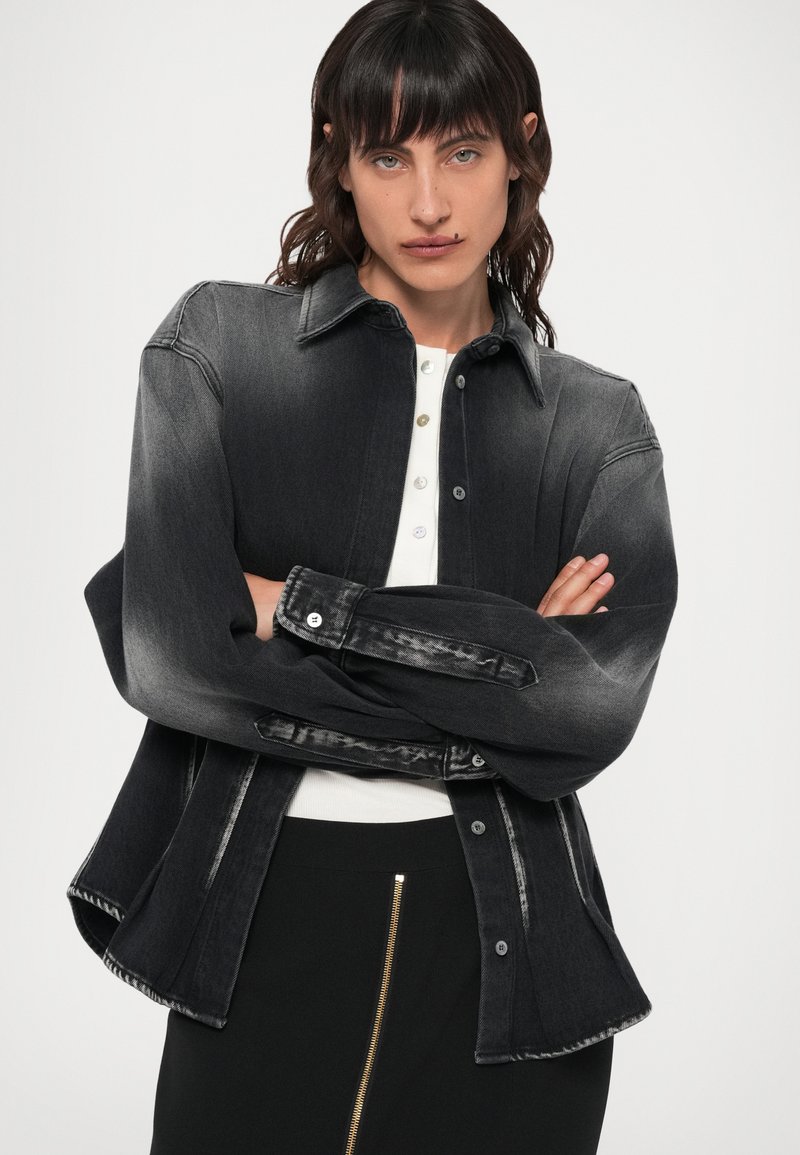 Svart denimskjorta med en gradientfade, knapprad fram, spetsig krage och långa ärmar. Matchad med en svart kjol med dragkedja.