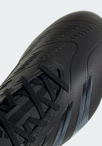Scarpa sportiva nera con tomaia sintetica testurizzata, dotata di lacci neri e distinte strisce angolari in un motivo a gradiente sul lato.