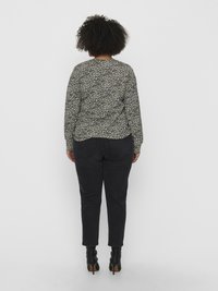TOP de mangas longas com padrão floral em preto e branco, com decote arredondado, combinado com jeans skinny pretos e botins de salto pretos.