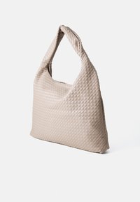 Gewebte beige Handtasche mit einem weichen, strukturierten Körper und einem einzelnen, runden Griff, der ein strukturiertes, geflochtenes Finish aufweist.