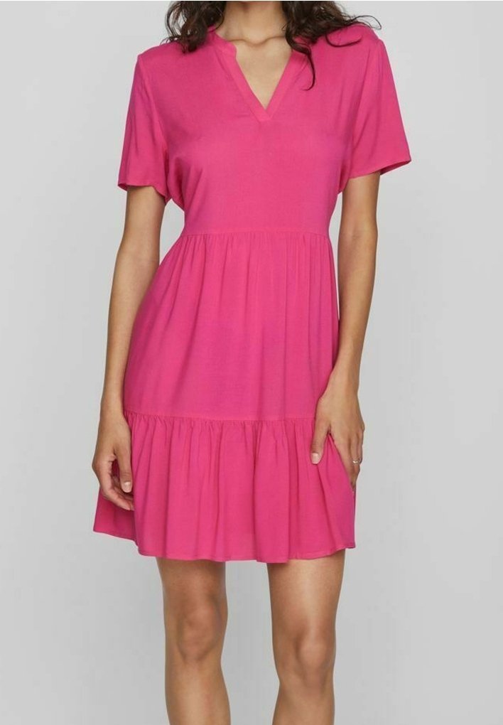 Robe rose courte avec des manches courtes, décolleté en V et un ourlet à volants superposés. Fabriquée en tissu léger et lisse avec une coupe décontractée.