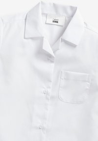 Chemise blanche à manches courtes en mélange de coton avec un col pointu, une fermeture boutonnée à l'avant et une poche sur la poitrine gauche. Texture lisse, design classique.