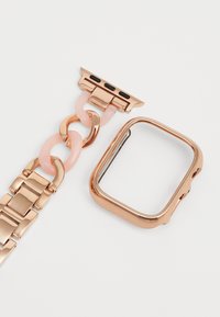 Satna za pametni sat u rose gold boji sa kvadratnim oblikom, uz lančanu narukvicu s ružičastim karikama i metalnim detaljima.