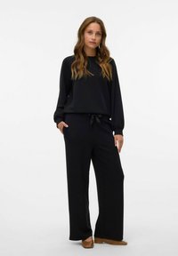 Conjunto de ropa de estar en casa negro que incluye una camiseta de manga larga y pantalones de pierna ancha con cintura ajustable. Confeccionado con tela suave y con un corte holgado.
