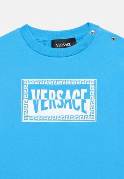 Μπλε φούτερ με στρογγυλή λαιμόκοψη, με λευκό λογότυπο "VERSACE" και περίγραμμα  με μοτίβο ελληνικού κλειδιού. Περιλαμβάνει διακοσμητικά κουμπιά στους ώμους.
