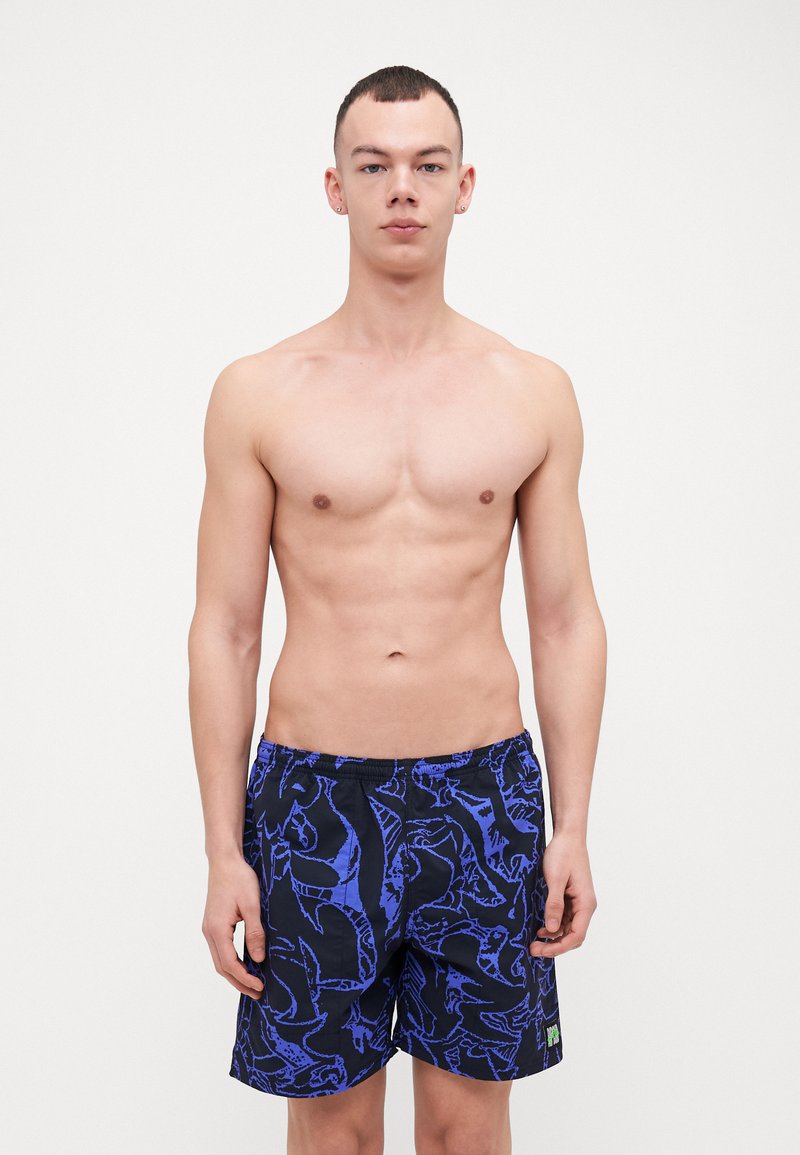 Pantaloni da nuoto neri con motivi astratti blu, vita elastica e una piccola etichetta verde all'orlo. Tessuto leggero.