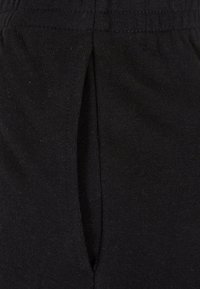 Schwarze Baumwollhose mit strukturiertem Finish, elastischem Bund und seitlichem Schlitztaschen-Detail.