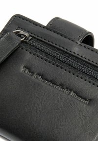 Portafoglio in pelle nera con scomparto zip e logo in rilievo "The Chesterfield Brand". Texture liscia con cuciture minime.