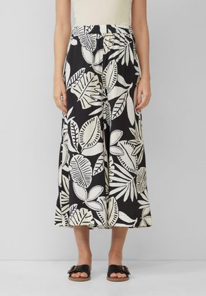Pantalons larges noirs avec un motif de feuilles blanches, fabriqués dans un tissu doux, dotés d'une taille élastique et de fentes sur les côtés.