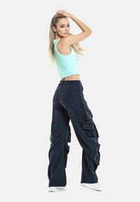 Navy cargo pants with loose fit, featuring multiple side pockets and textured detailing. Paired with a fitted mint crop top.