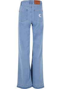 Vyblednuté modré nohavice širokého strihu vyrobené z denimu, s vysokým pásom, zadnými vreckami a hnedou koženou nášivkou s detailom loga.