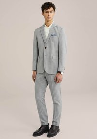 Pelēka strīpota uzvalka ar šūtu žaketi un šaurām biksēm. Iekļauts gaismas krāsas krekls un tumša ādas kurpes. Ieraksts kabatas lakatiņam.