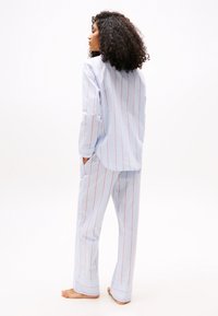 Light blue striped pajama set with red lines. The shirt features a relaxed fit and long sleeves, while the pants have pockets and a straight leg design.