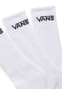 Calze bianche a coste con il logo "VANS" nero sulla parte superiore. Il tessuto sembra morbido con una superficie liscia. Sono visibili tre paia.