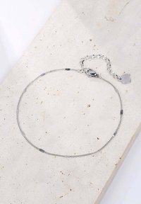 Bracciale in argento con maglie alternate lisce e texturizzate, dotato di chiusura a moschettone e un piccolo ciondolo a forma di cuore.