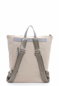 Mochila beige con acentos plateados, doble tirante y asas en la parte superior. Presenta un bolsillo con cremallera y un diseño plano con textura suave.