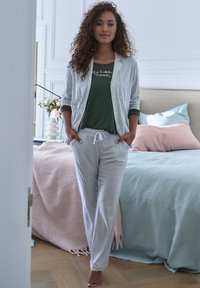 Striped long-sleeve jacket and matching pants in light blue and white; green top with white text; soft fabric; relaxed fit.