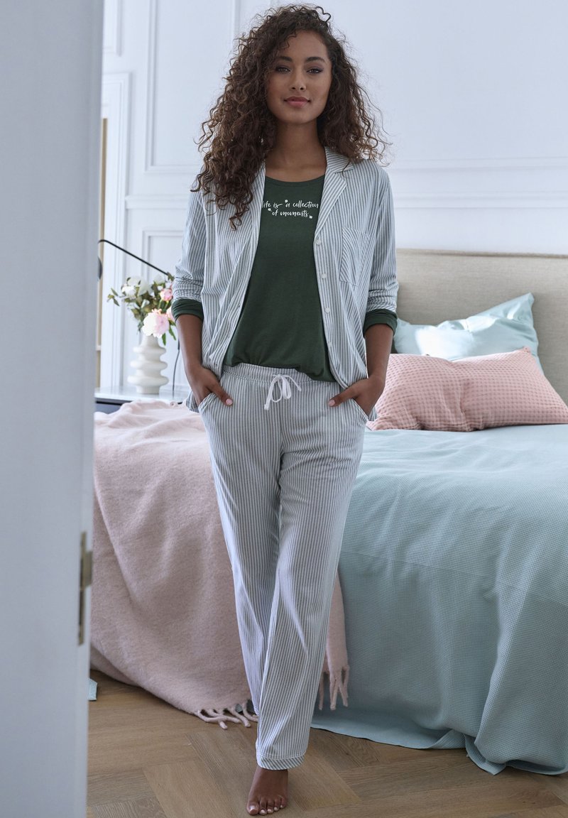 Striped long-sleeve jacket and matching pants in light blue and white; green top with white text; soft fabric; relaxed fit.