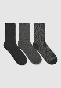 Tre paia di calze: nere uni, grigio scuro testurizzato con un motivo a macchie, e nere con un design a strisce zebra lucide.
