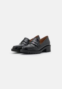 Schwarze Lacklederschuhe mit einem kräftigen Absatz, ausgestattet mit doppelten Riemenakzenten und einer strukturierten Sohle für zusätzlichen Halt. Klassisches und vielseitiges Design.