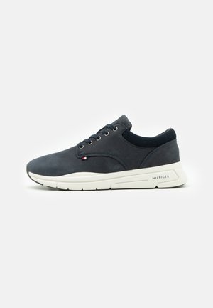 Sneakers z ciemnoniebieskiej zamszowej cholewki, sznurowane, z białą gumową podeszwą. Posiadają boczne logo i wyściełany kołnierz dla wygody.