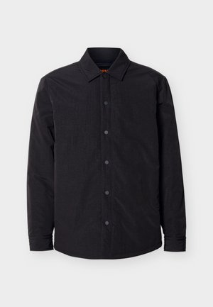 Veste-chemise noire à manches longues avec fermeture à boutons-pression, col pointu et ourlet légèrement incurvé sur un fond clair.
