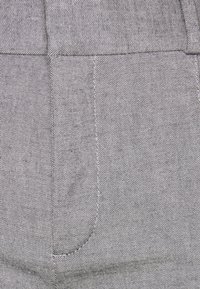 Grå denimtyg med en diagonal väv, med en subtil lyster och sydda detaljer runt fickorna och sömmarna.