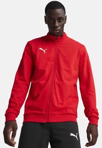 Rote Puma-Trainingsjacke mit hohem Kragen, gerippten Bündchen und Saum, mit weißem Logo auf der linken Brust. Glatte Stoffoberfläche.