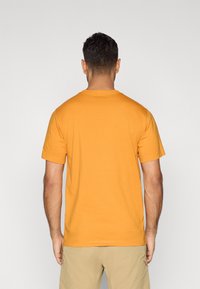 Κοντομάνικη μπλούζα T-shirt σε ζωηρό πορτοκαλί βαμβακερό ύφασμα με στρογγυλή λαιμόκοψη, με ίσια γραμμή και απλή πλάτη.