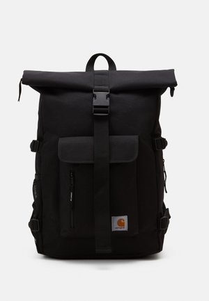 Sac à dos noir à rabat enroulable en tissu durable, doté d'une poche frontale, de bretelles ajustables et d'un patch logo de la marque. Texture globale lisse.