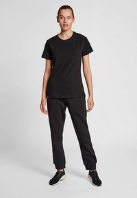 Sort bomuld t-shirt med korte ærmer kombineret med sorte sweatpants med en tilspidset pasform og letvægtsstof. Sorte sneakers inkluderet.