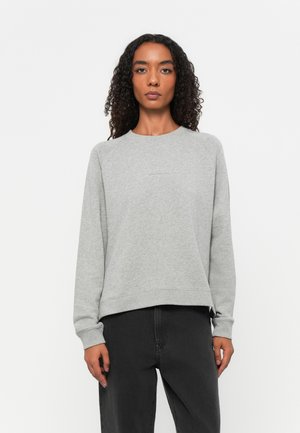 Grijze sweatshirt met een ronde halslijn en raglan mouwen. Beschikt over een iets verkorte zoom en een zachte stoftextuur. Gepaarde met donkere broeken.