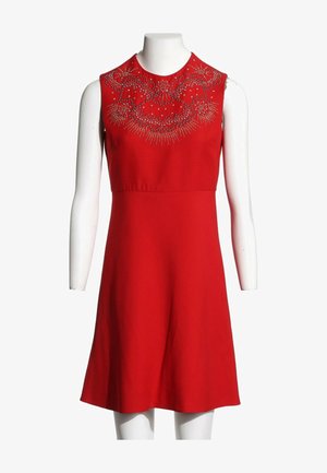 Robe rouge sans manches avec corsage ajusté et motif floral orné de bijoux autour de l'encolure, exposée sur un mannequin blanc.