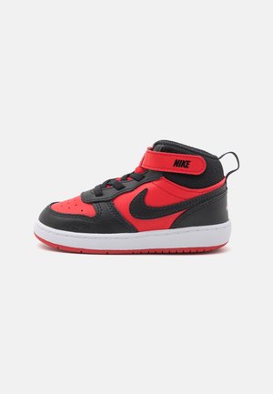 Rød og sort høj sneaker fra Nike med hvid sål, sort swoosh, sorte snørebånd og en rød velcrolukning med Nike-logo.