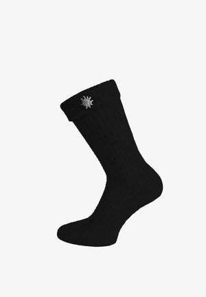 Black ribbed knee-high sock with a folded cuff and a small silver flower-shaped emblem on the outer side near the top.