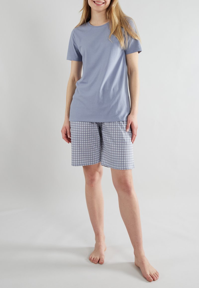 T-shirt in cotone azzurro abbinato a pantaloni corti a scacchi in azzurro chiaro e bianco. I pantaloni corti presentano una vita elastica e tasche.