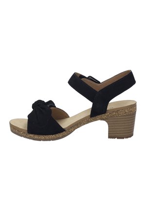 Black suede sandal with a knotted front detail, adjustable strap, and a cork-textured heel. Features a flat, textured sole.