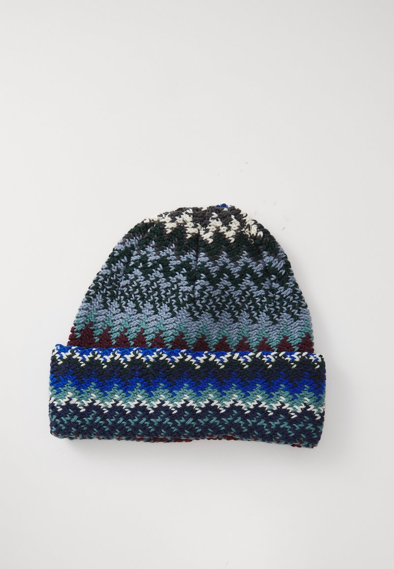 Knitted beanie with folded brim in blue, green, maroon, black, and white zigzag and geometric pattern on a white background.