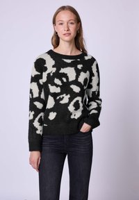 Maglione lavorato a maglia con un motivo astratto in bianco e nero, scollatura tonda, maniche lunghe e polsini e orlo a costine.