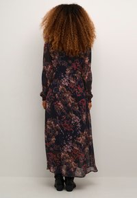 Long, floral dress with a dark navy background, featuring pink and red flowers. Made of sheer fabric with long sleeves and a relaxed fit.