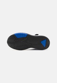 Suola di scarpa sportiva in gomma nera con accenti blu. Trazione testurizzata con motivo geometrico e zona del tallone rinforzata.