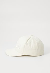 Hvid baseballkasket med broderet tekst på fronten, buet skygge, seks-panel design og små ventilationshuller på siderne.