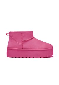 Botines rosas de material suave, con punta redonda, suela plana y una lengüeta en la parte trasera para ponerlos y quitarlos fácilmente.