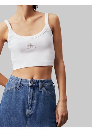 Witte geribbelde crop top met dunne bandjes en een vierkante halslijn, met een klein Calvin Klein Jeans-logo op de voorkant. Blauwe denim rok met hoge taille.