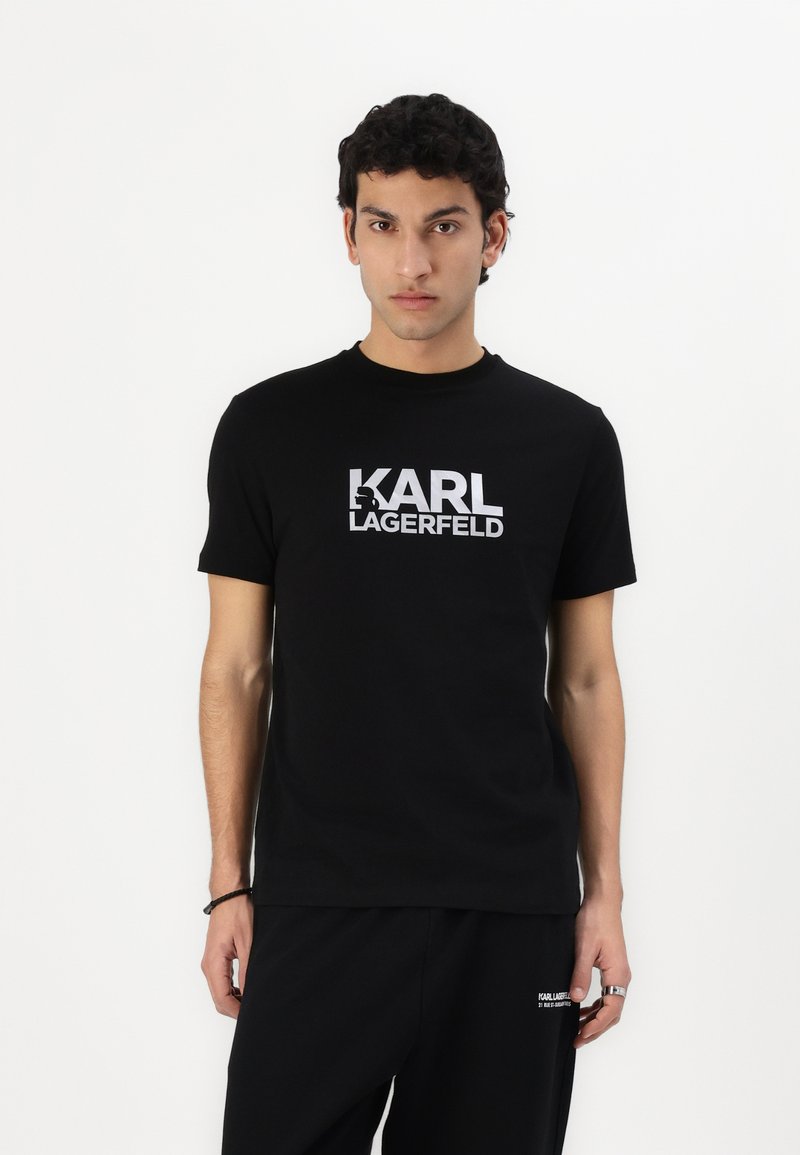 Μαύρο βαμβακερό μπλουζάκι με έντονο λευκό λογότυπο "KARL LAGERFELD", στρογγυλή λαιμόκοψη, κοντά μανίκια και χαλαρή εφαρμογή.