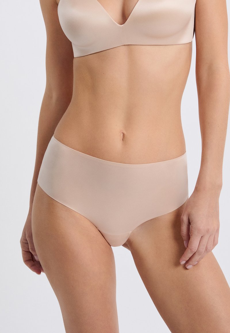 Culotte beige sans couture avec une texture lisse et un design taille haute, arborant un style minimaliste et sans coutures visibles pour un ajustement flatteur.