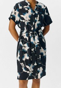 Kurzärmliges Kleid aus schwarzem Stoff mit abstrakten blauen und weißen Blumenmustern, Kragen, durchgehenden Knöpfen und einem passenden Gürtel.