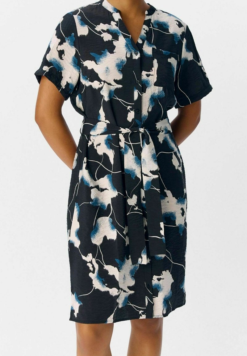 Kurzärmliges Kleid aus schwarzem Stoff mit abstrakten blauen und weißen Blumenmustern, Kragen, durchgehenden Knöpfen und einem passenden Gürtel.